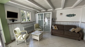 A room with a TV, two chairs, a sofa, and a table.