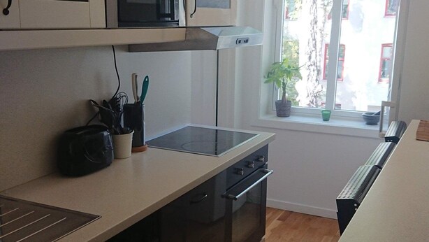 A kitchen with a microwave, stove, and a window with a view of trees. - S12-3rd Floor Casa Grunerlokka (Oslo)