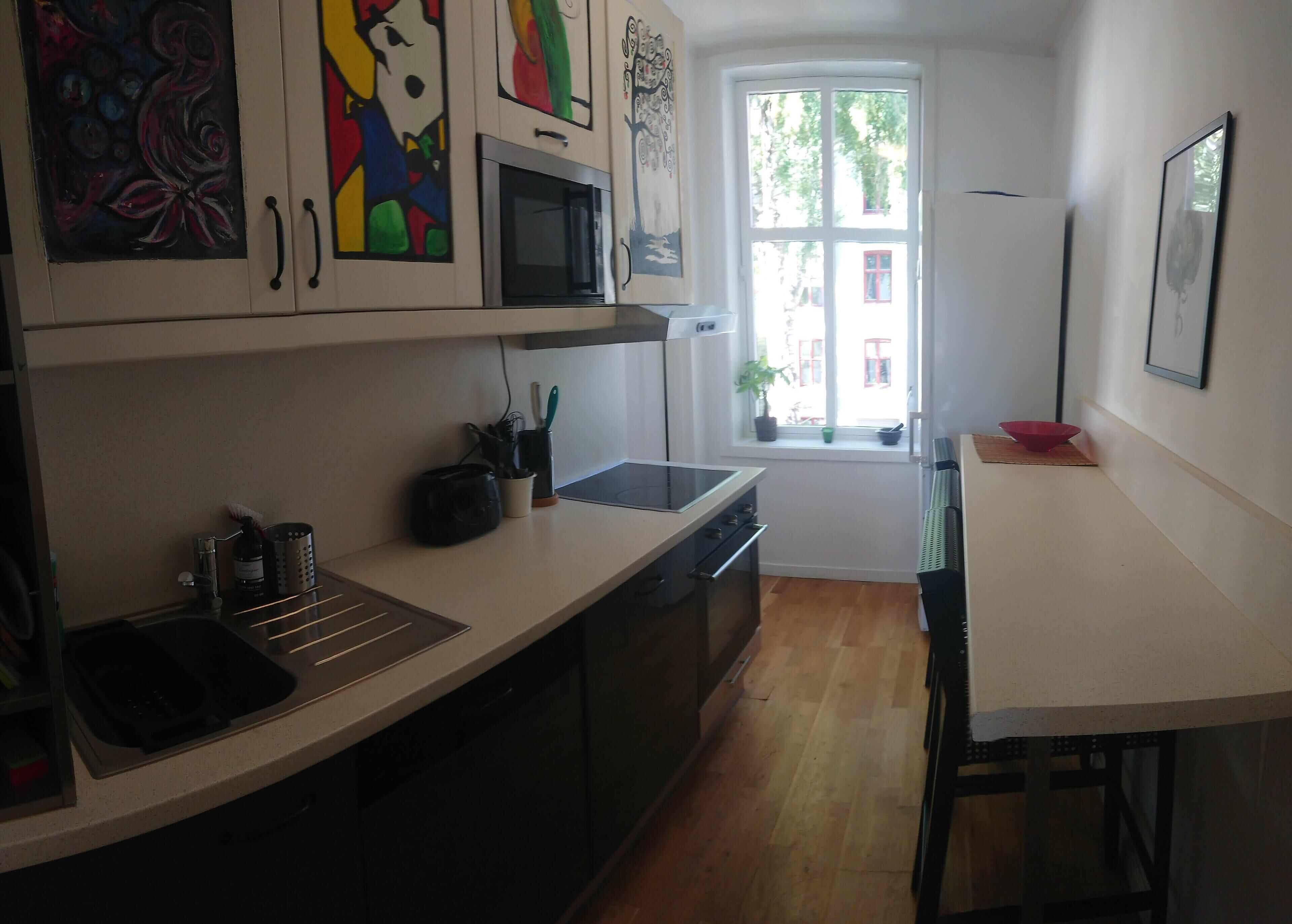 Una cucina compatta con forno a microonde, fornello e lavello. Una finestra offre vista all'esterno.