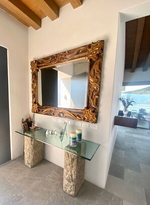 A bathroom with a large ornate mirror, a glass vanity, and two stone bases.