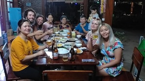 A group of people sitting around a wooden dining table with various dishes and drinks. - Tam Coc Melody Homestay (Nam Hoa Lu)