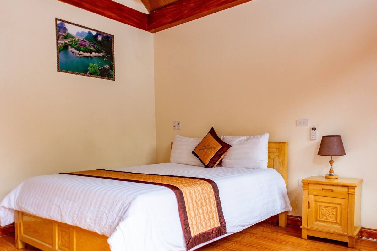 Une chambre à coucher avec un lit en bois, une table de chevet, une lampe et un tableau accroché au mur.