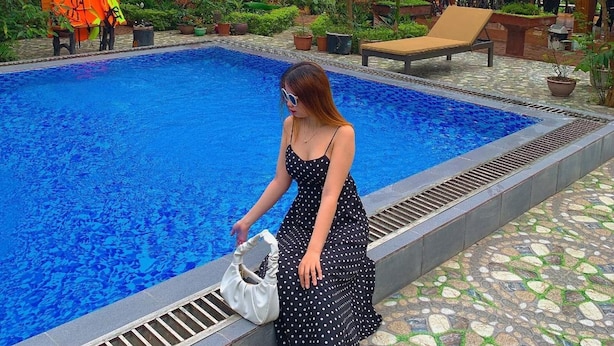 A swimming pool with a tiled edge, surrounded by greenery and a brick building. - Tam Coc Melody Homestay (Nam Hoa Lu)
