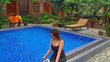 Una piscina al aire libre, sillones reclinables de piscina