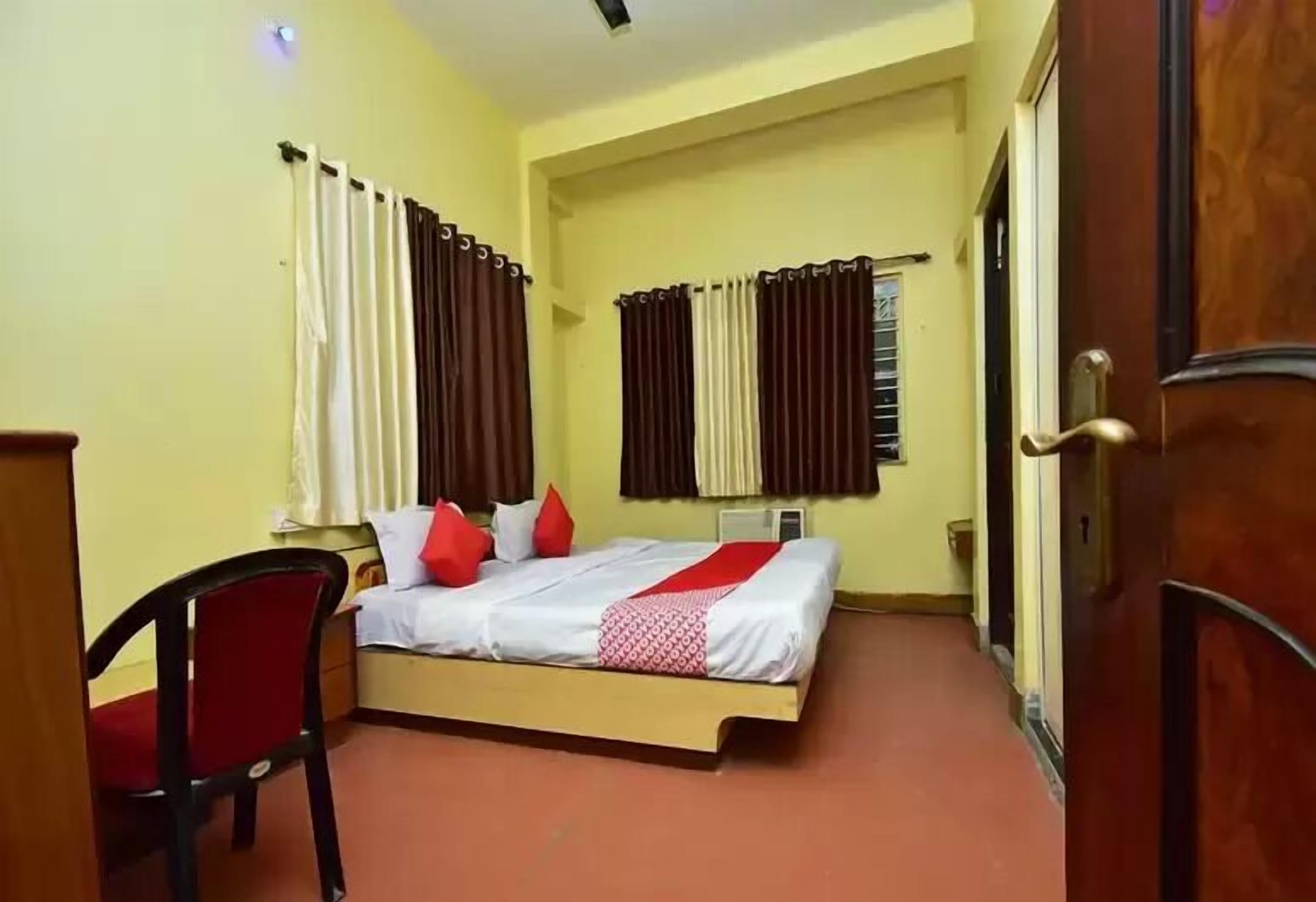 A bedroom with a bed, a chair, and curtains.