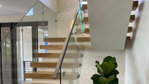 Una escalera moderna con barandillas de vidrio y escalones de madera.