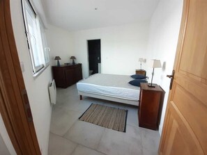 Une chambre à coucher avec un lit, des tables de chevet, une commode, une fenêtre et une porte.