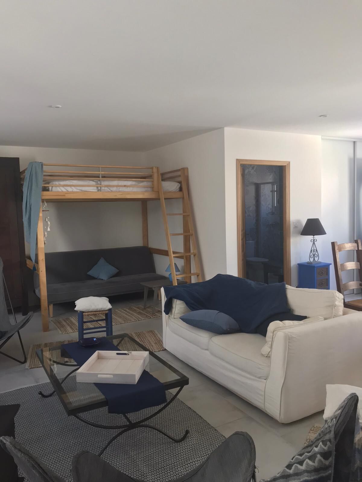 Uma sala de estar com uma cama beliche, um sofá, uma mesa de centro e uma cadeira.