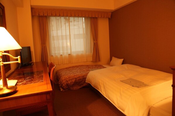 A hotel room with a bed, a desk with a lamp, a chair, a window with curtains, and a television. - Nonsmoking studio twin  Without meals With fri / Sendai Miyagi (Sendai)