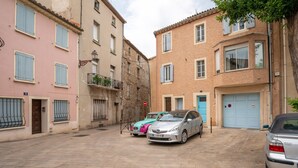 A narrow street with parked cars and buildings with traditional architecture.