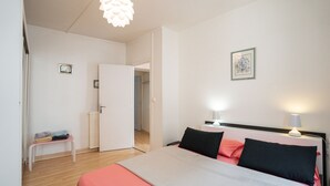 A bedroom with a bed, bedside lamps, a small table, and a radiator.