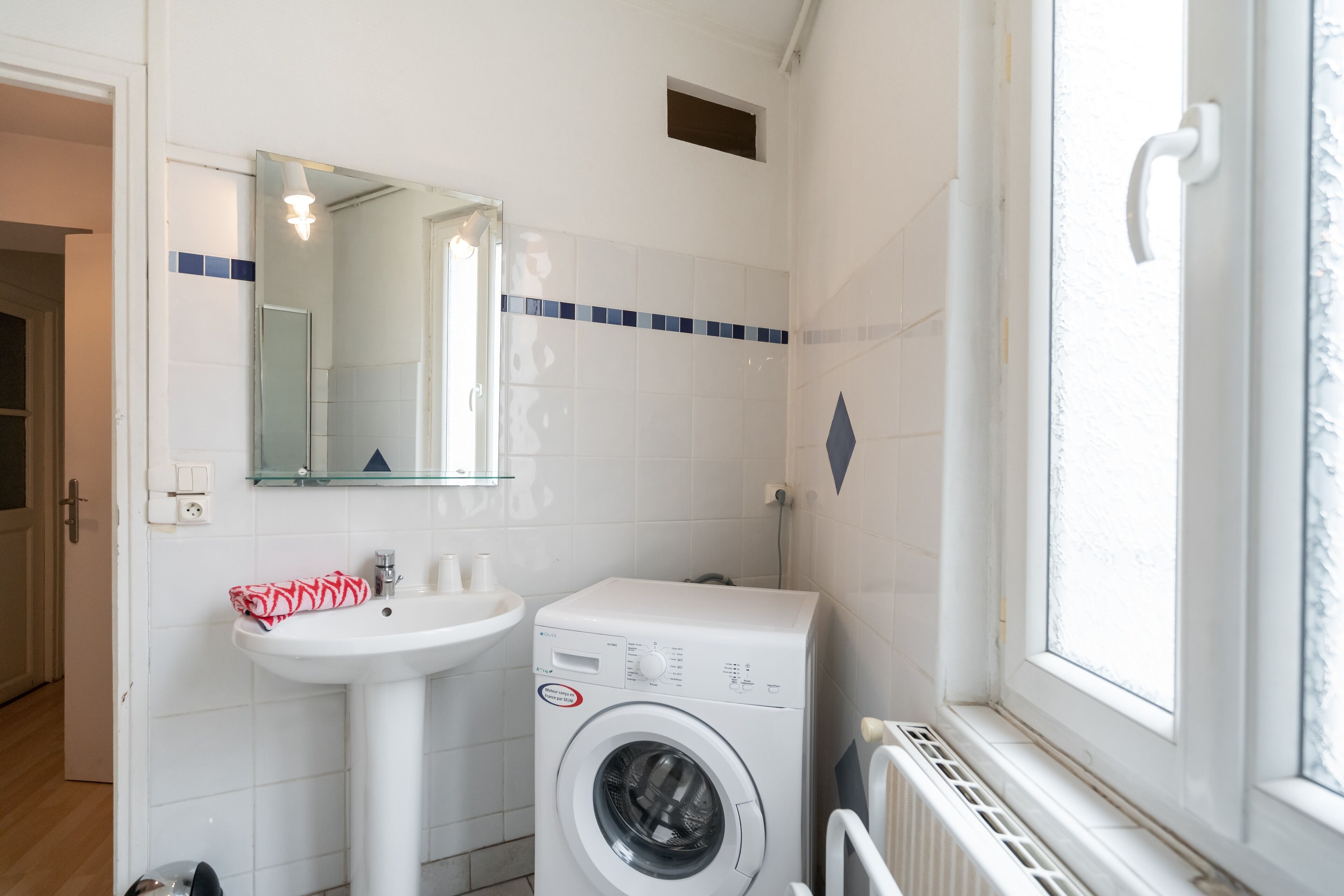 Une salle de bain équipée d’un lave-linge, d’un lavabo et d’un miroir.