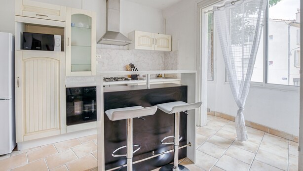 A kitchen with a microwave, oven, and a bar area with stools.