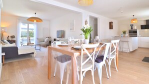 Un vaste espace de vie comprenant une table à manger pour quatre personnes, un canapé et une cuisine en arrière-plan.