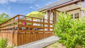 A wooden deck with a yellow umbrella, a potted plant, and a house with a visible address.