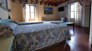 Een kamer met twee bedden, een plafondventilator, een schilderij en een raam met gordijnen.