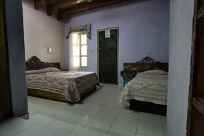 Een slaapkamer met twee bedden, een deur en een raam.