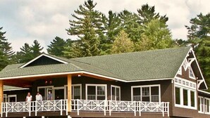 A lodge with a covered porch and a large windowed section. - Lake Placid Club Boat House Residences 3 Bedroom (Lake Placid)