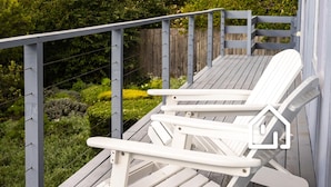 Una terraza de madera con dos sillas Adirondack blancas.