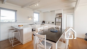 Una cocina moderna con armarios blancos, una isla central y taburetes de bar.