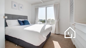 Un dormitorio con una cama grande, una ventana con cortinas y vistas a zonas verdes.