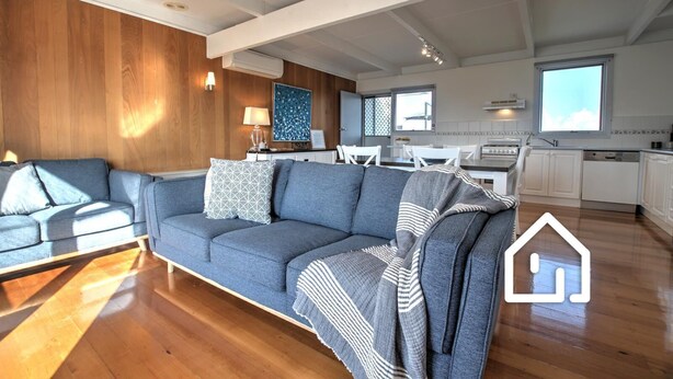 Una sala de estar moderna con un sofá, comedor y cocina.