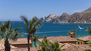 A coastal view with terracotta-roofed buildings, palm trees, and a clear blue sea. - Cabo Dream Stay-4BR Oceanview at Hacienda Beach Club can be rented as 2-3 bedrm (Cabo San Lucas)