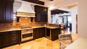 A kitchen with dark wooden cabinets, a tiled backsplash, and a large island with a built-in oven. - Cabo Dream Stay-4BR Oceanview at Hacienda Beach Club can be rented as 2-3 bedrm (Cabo San Lucas)