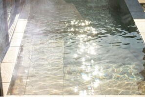 Reflective water feature with a smooth, still surface, bordered by a tiled edge.