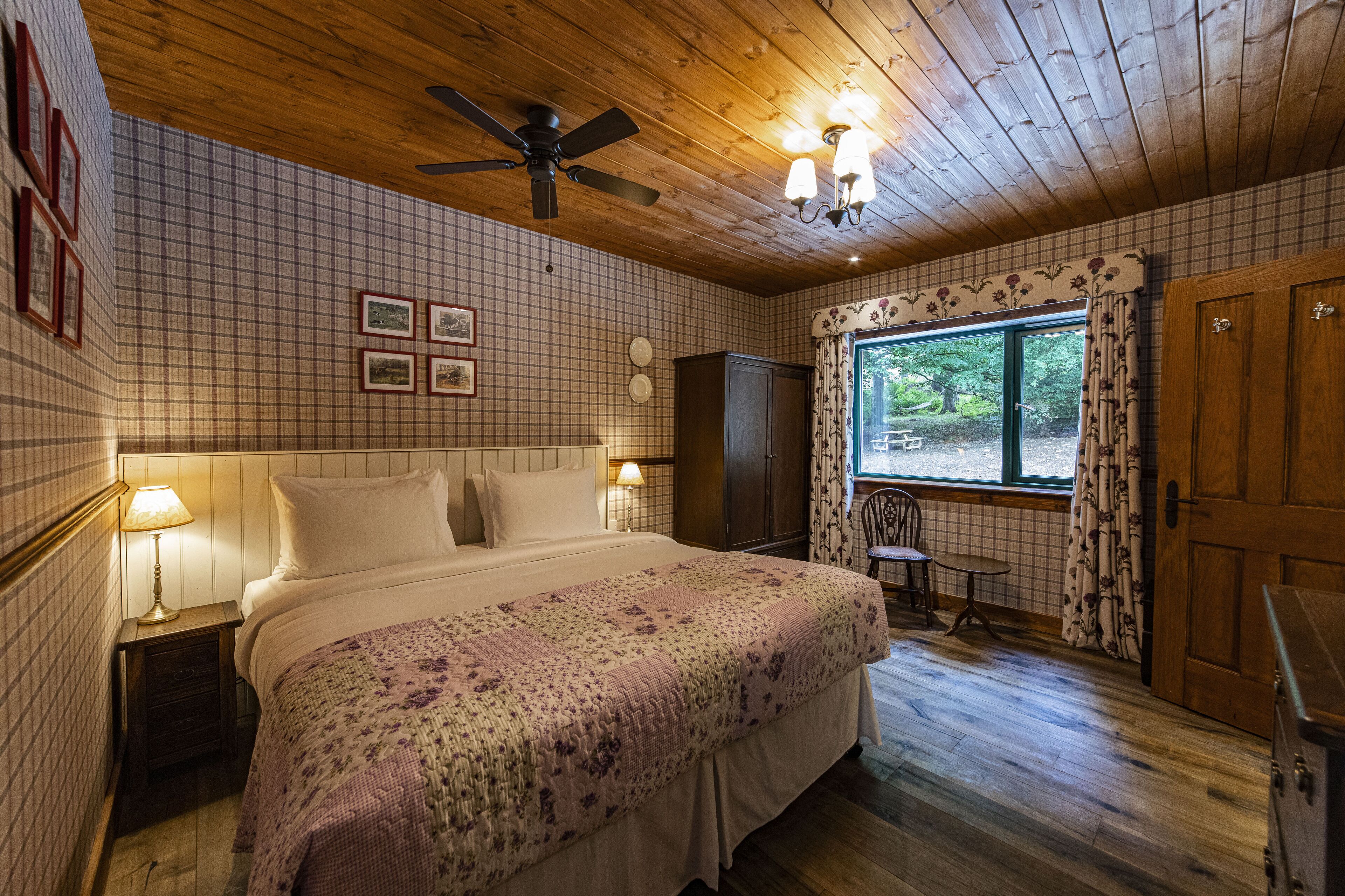 Un dormitorio acogedor con una cama grande, un ventilador de techo y una ventana con cortinas.
