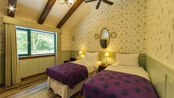 A room with two beds, wooden floors, a ceiling fan, and a window with curtains.