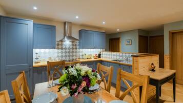 A modern kitchen with blue cabinets, a central island, and a dining table set for four.