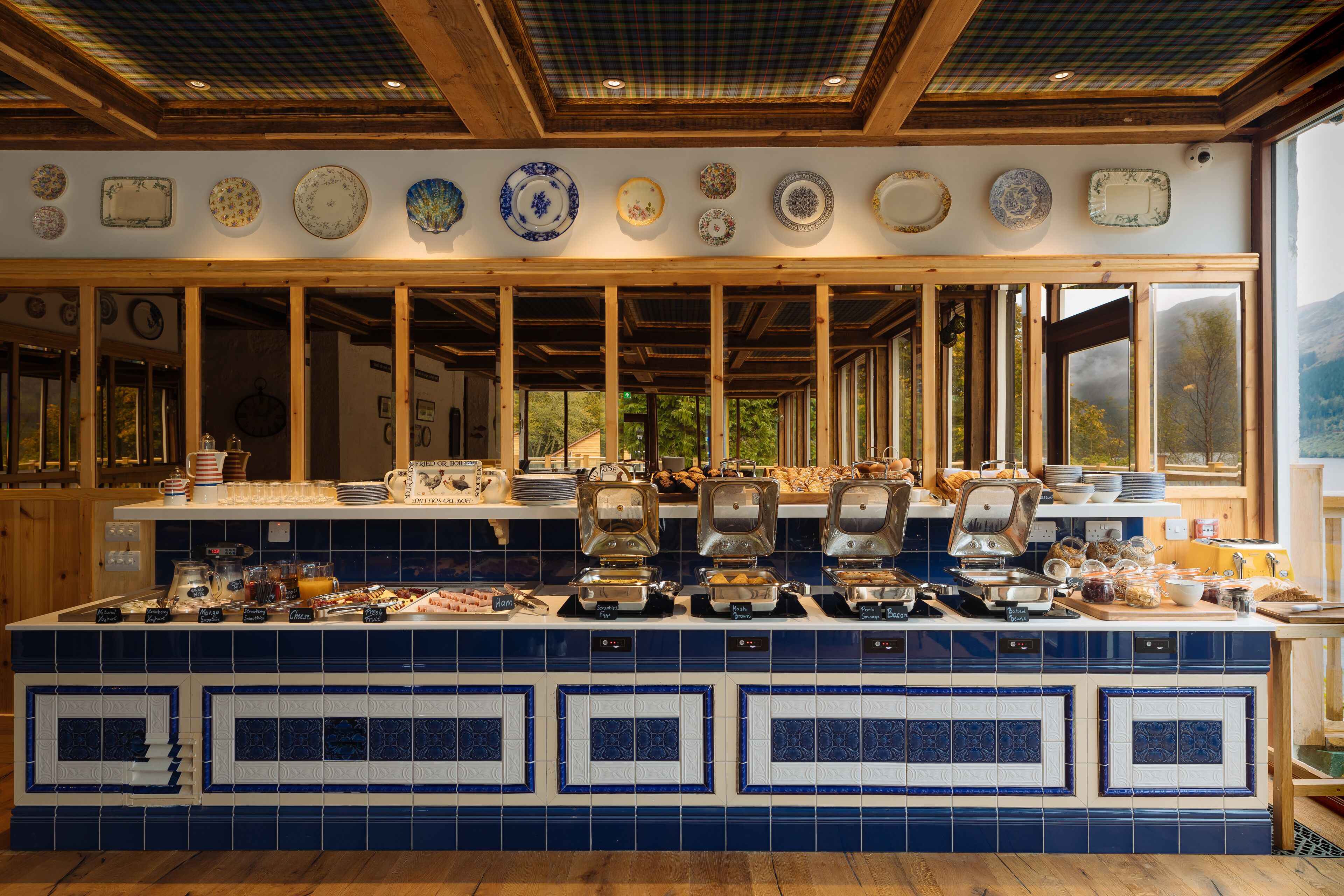 Une cuisine avec un mur recouvert de carreaux bleus, des poutres en bois et une variété de plats exposés sur le mur.