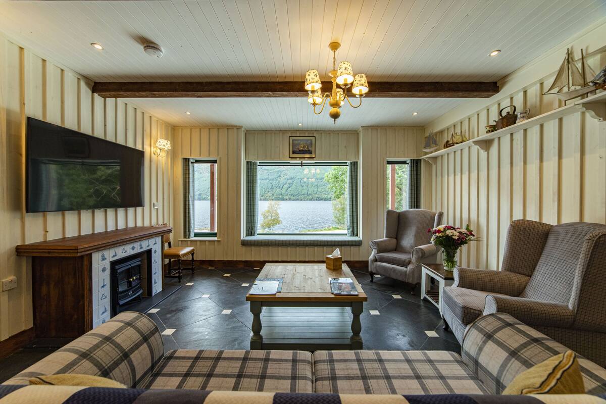 Una sala de estar con chimenea, televisor, mesa de centro y sofá.