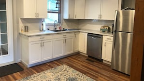 Uma cozinha moderna com armários brancos, eletrodomésticos de aço inoxidável e um tapete estampado.