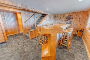 Ein Holzinnenraum mit Barbereich, einer Treppe und einem Teppichboden.