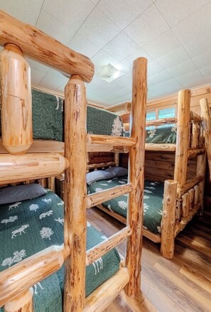 Ein Ferienhäuschen-Innenraum mit Holzbettställen und einer Klapptreppe.