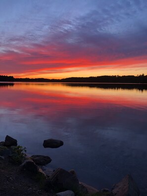 Ein ruhiger See bei Sonnenuntergang mit einem deutlichen Spiegelbild des Himmels.