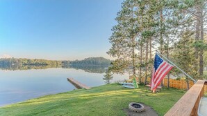 A lakeside property with a flag, a wooden deck, and a grassy area. - Fall Colors, ATV Trails & Lake Fishing Retreat (Crystal Falls)