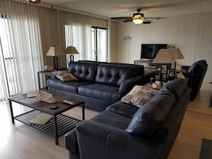 A modern living room with a dark leather sofa, a wooden coffee table, and a television.
