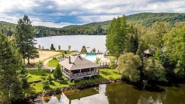 Une propriété au bord du lac, comprenant une maison, une piscine et un quai.