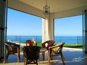 Relax on the balcony with ocean views, wicker chairs, and a small table.