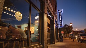 A street view at dusk with a restaurant named 'Salem' on the left, a 'Dine Out' sign, and a 'Salem' sign on a building to the right. - The Lofts at Downtown Salem (Salem)