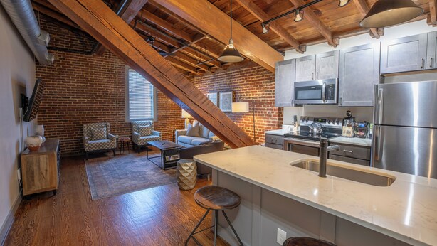 A kitchen with a large island, stainless steel appliances, and exposed wooden beams. - The Lofts at Downtown Salem (Salem)