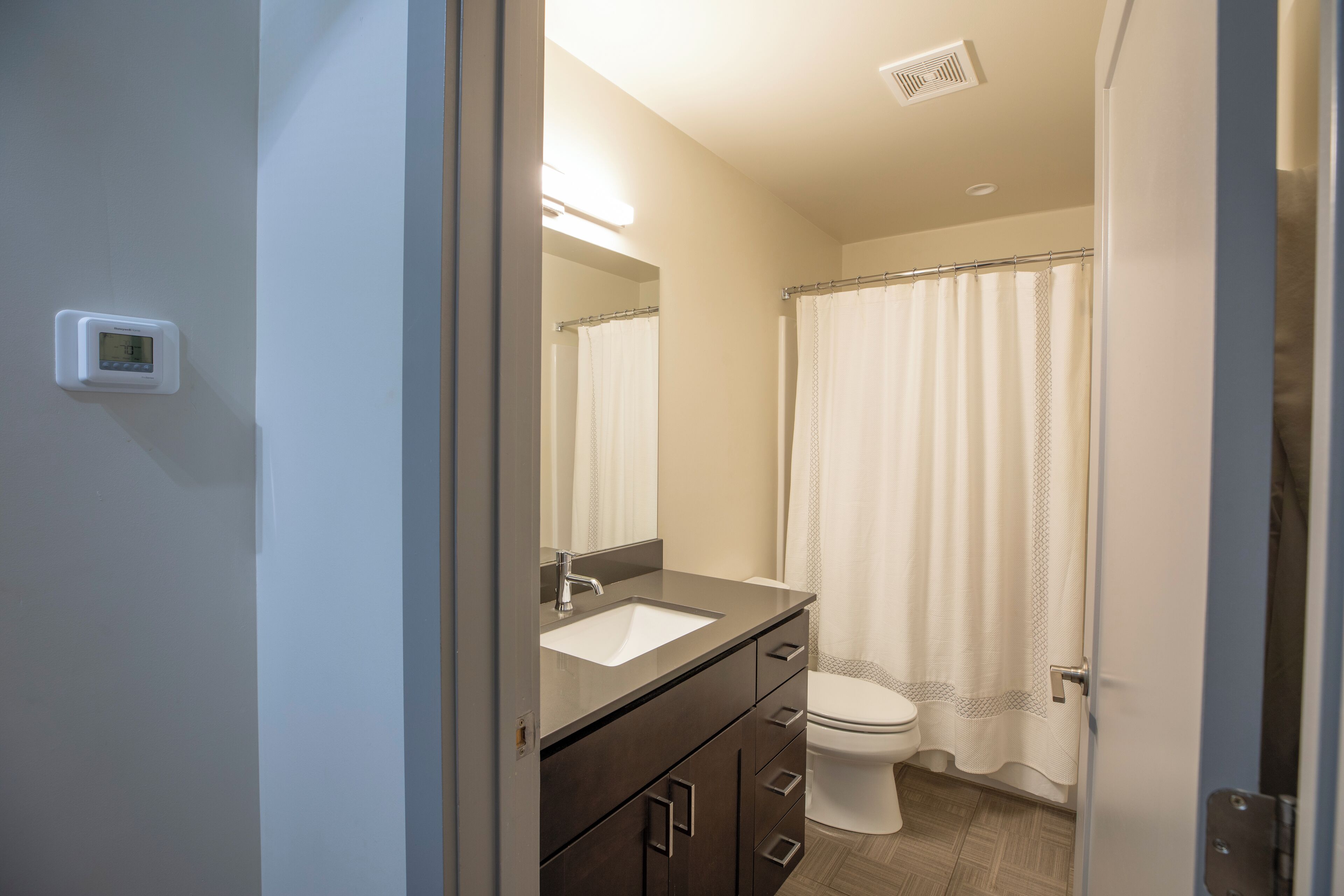 A bathroom with a white sink, dark cabinets, a toilet, and a shower curtain.