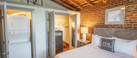 A bedroom with a bed, a nightstand, a lamp, a dresser, and a walk-in closet.