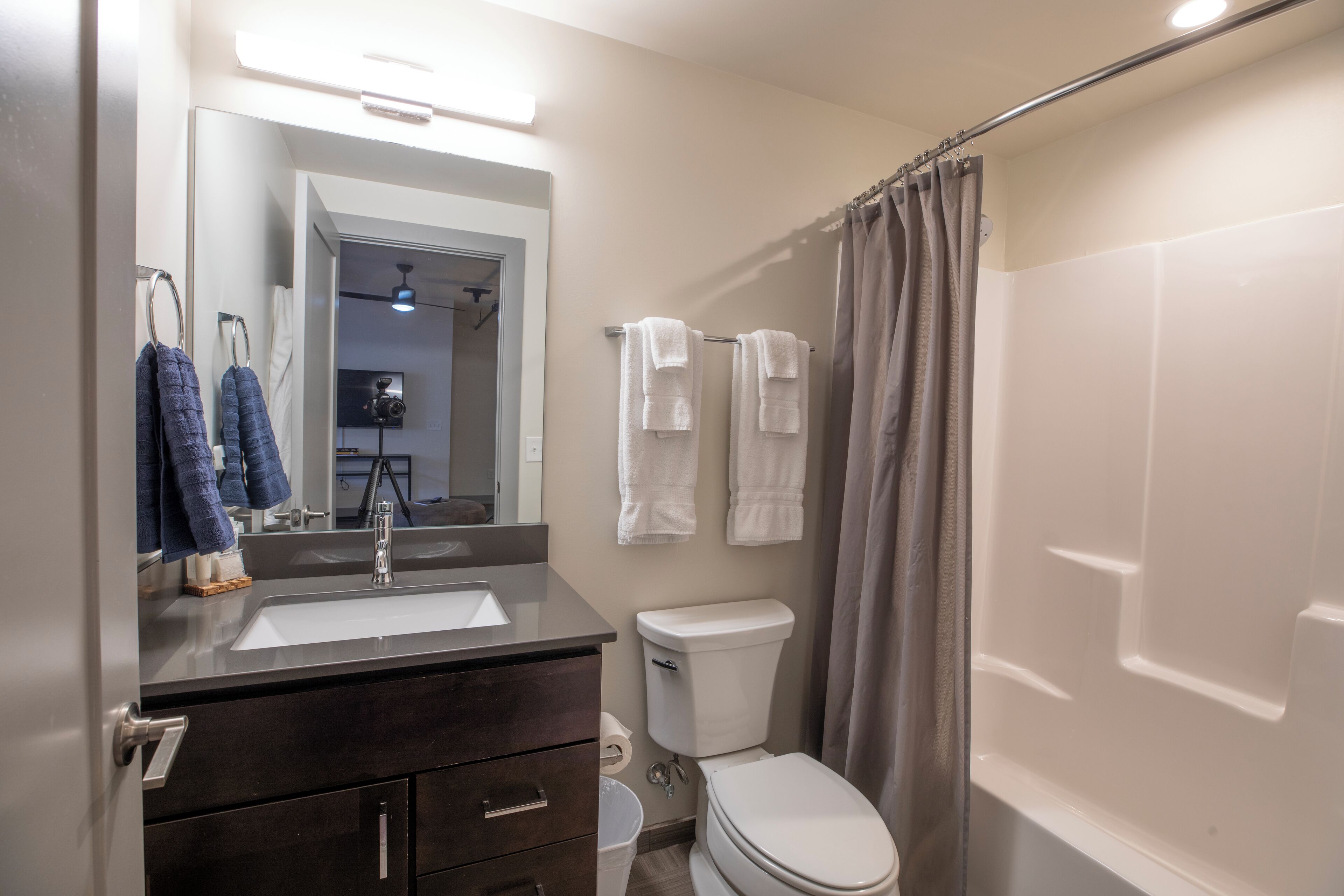 Une salle de bain équipée d’un lavabo, d’un miroir, de toilettes et d’un rideau de douche.