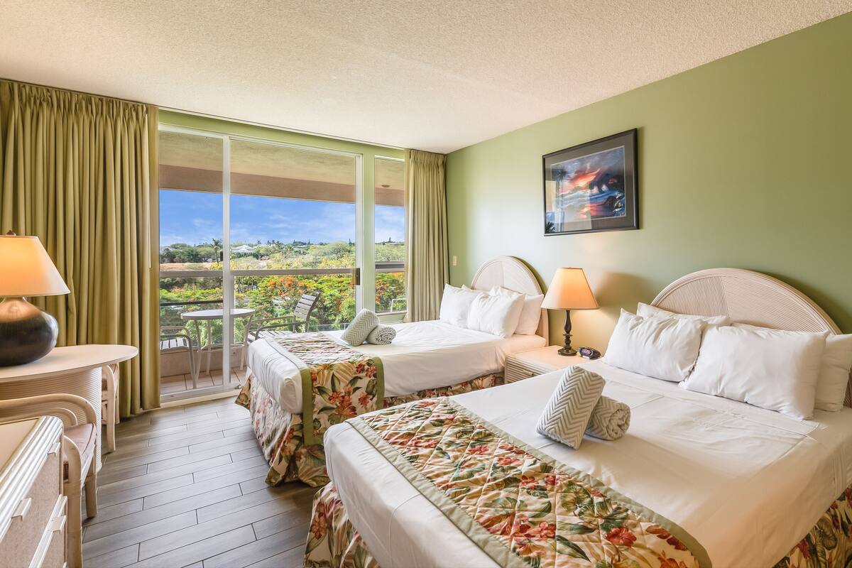 Una habitación de hotel con dos camas, un balcón con vistas y un cuadro en la pared.