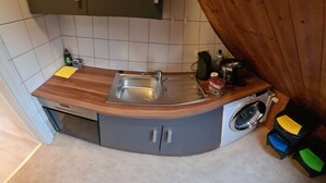A compact kitchen with a sink, a washing machine, and a small countertop. - W4, apartment with air conditioning, 2 bedrooms with 4 single beds. (Hüllhorst)