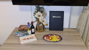 A table with snacks, a bottle of wine, a box of chocolates, and a vase with flowers. - W4, apartment with air conditioning, 2 bedrooms with 4 single beds. (Hüllhorst)